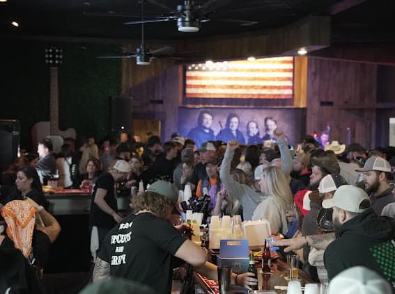 The crowd at the bar under the Outlaws mural
